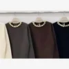 Maglia con collana dorata nei colori nero, marrone, panna e verde